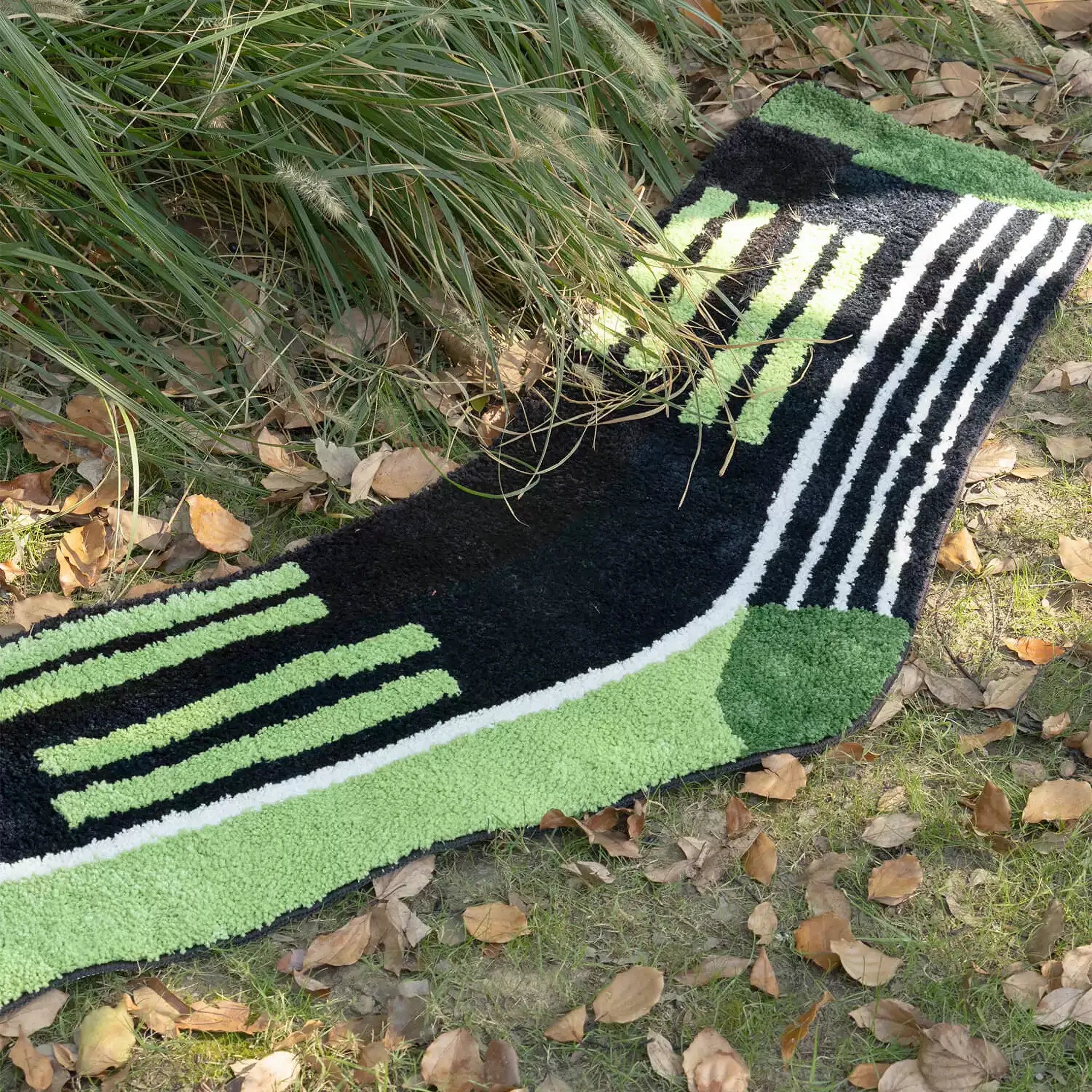 Black and green oversized sock rug with raised green and white stripes styled on grass by Housenfriends