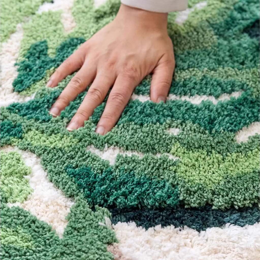Cassia Forest Green Monstera Leaf Irregular Tufted Rug, hand brushing the tufted pile to show softness