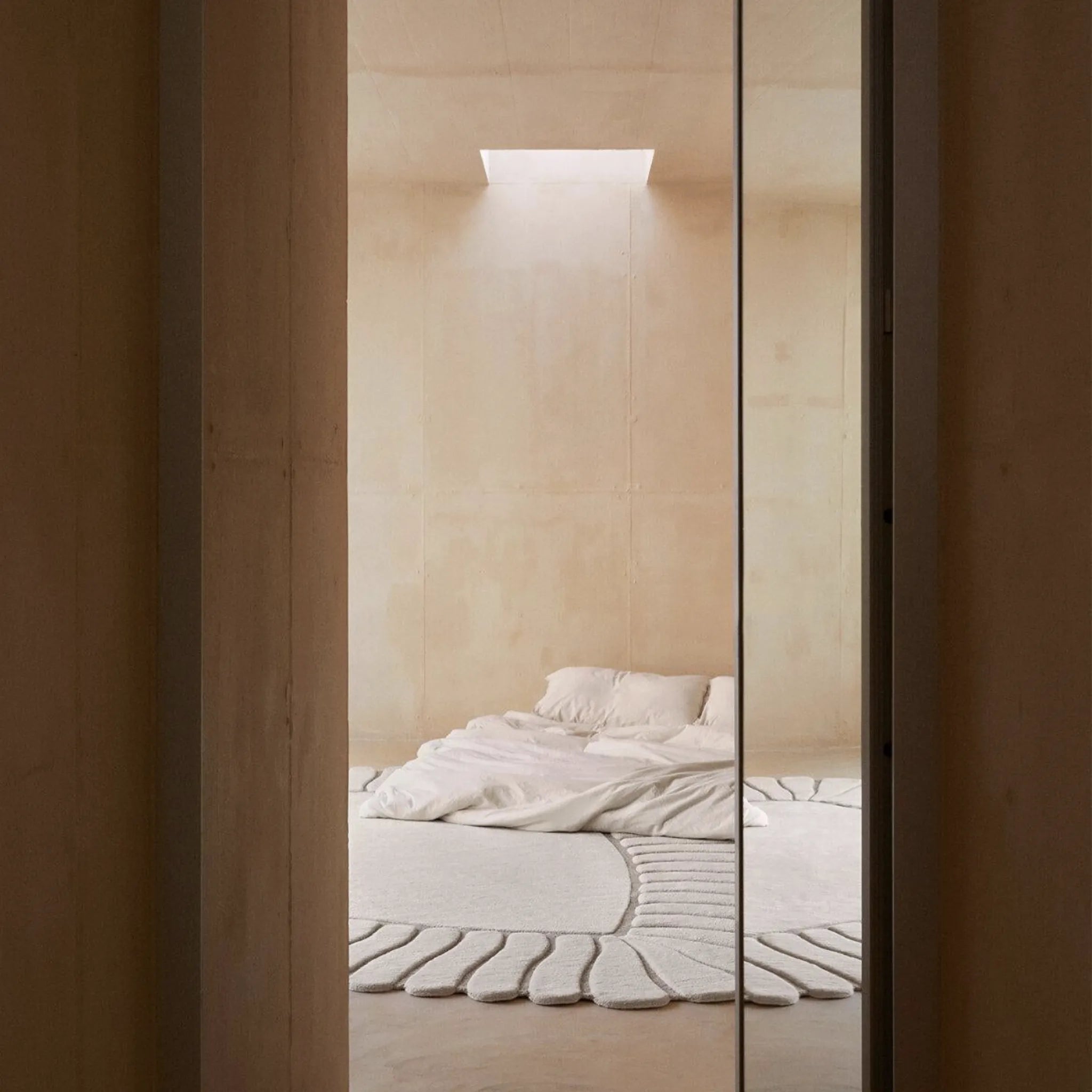 Minimalist bedroom with a bed and Coquille Cream Seashell Shaped Sculpted Rug by Housenfriends