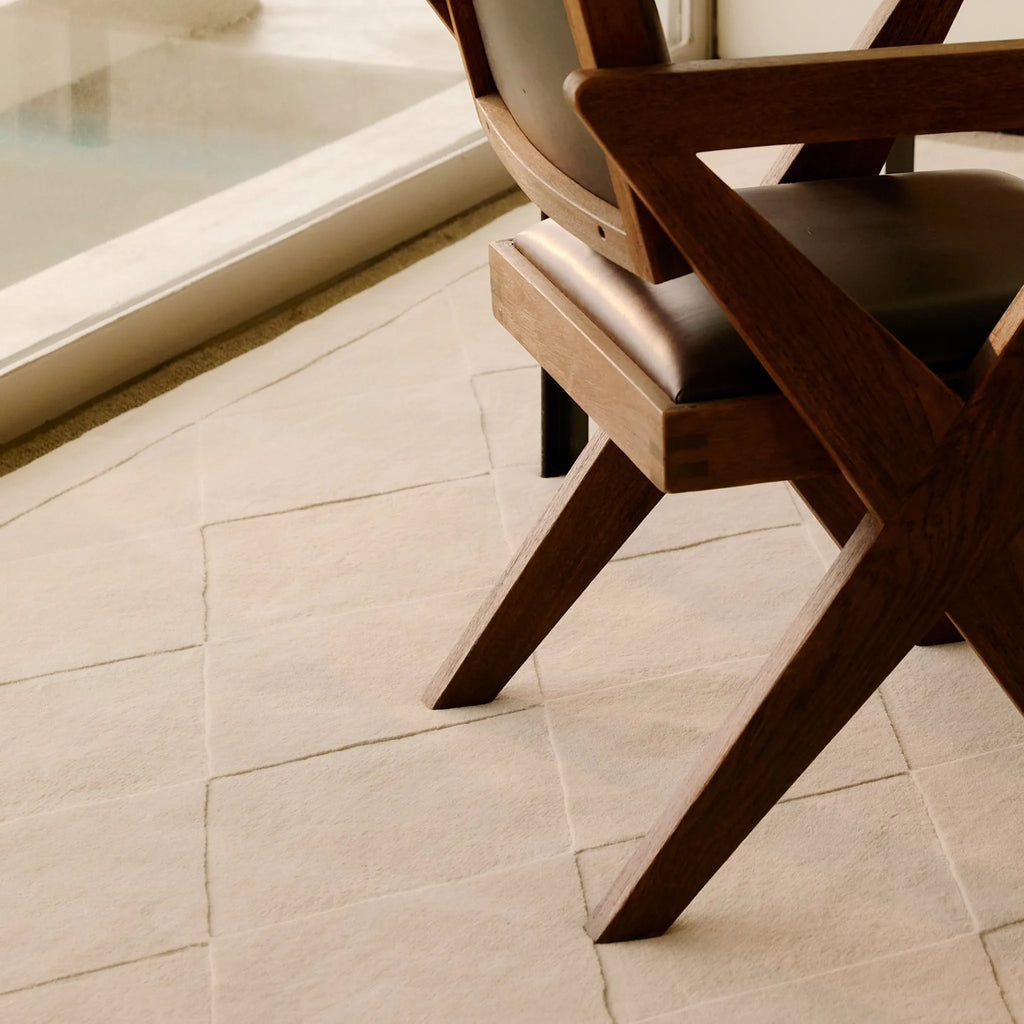 Wooden chair on the Cream Diamond Modern High Low Hand Tufted Rug by Housenfriends