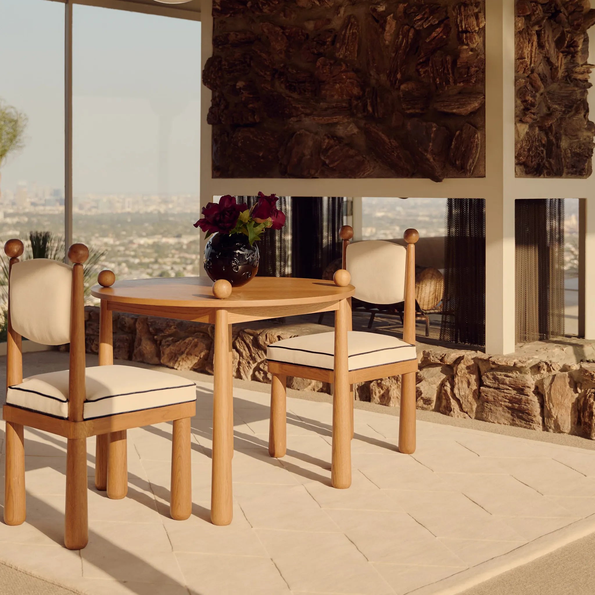 Cream Diamond Modern High Low Hand Tufted Rug under a wooden dining table and chairs, with a cityscape in the background.