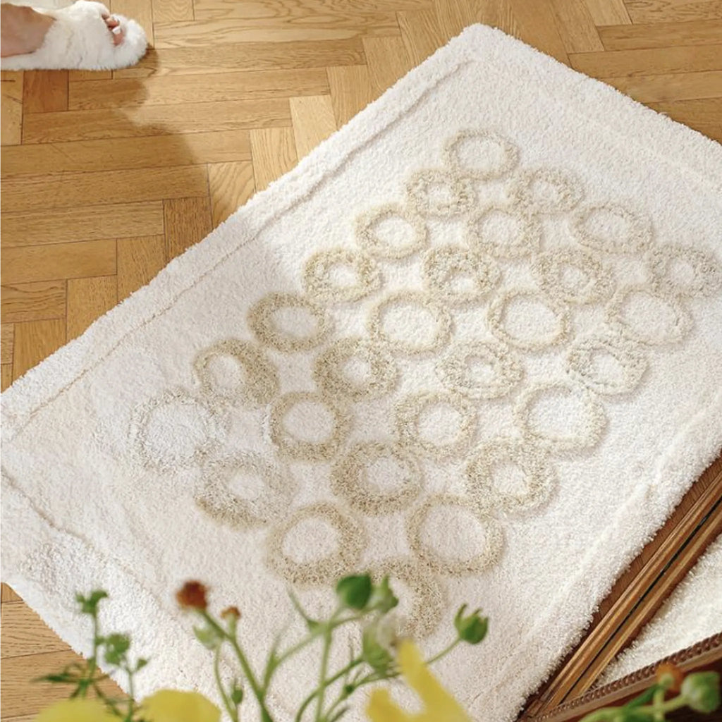 Nola Cream Base Beige Sculpted Circle Tufted Rug on a wooden floor