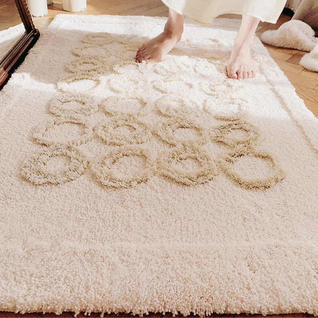 Close-up of a textured cream tufted rug with beige circle on a wooden floor.