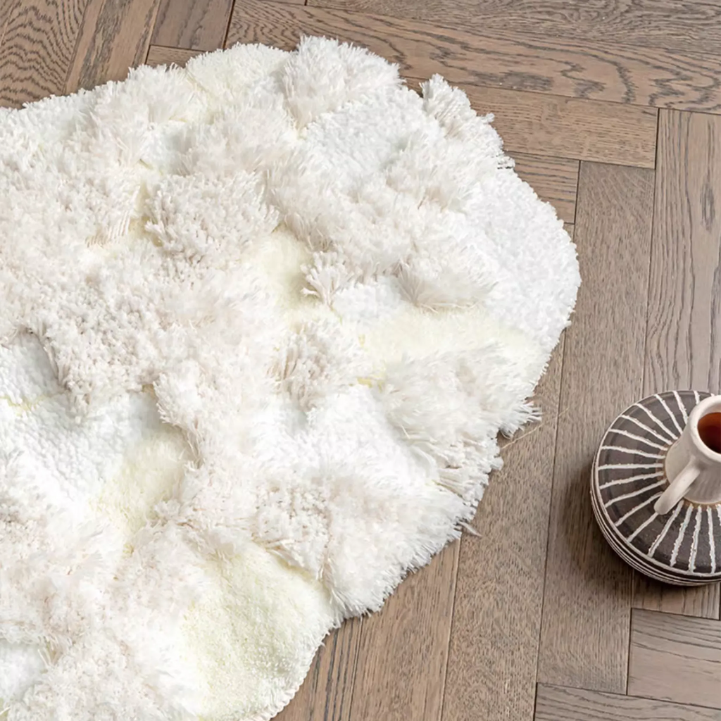 Eira Off White Irregular Cloud Patch High Low Tufted Rug by Housenfriends, full view of the irregular cloud-patch shape on a herringbone wood floor.