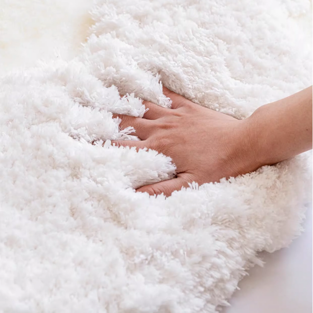 Eira Off White Irregular Cloud Patch High Low Tufted Rug by Housenfriends, hand pressing into the fluffy pile to show softness and depth of the high-low texture.