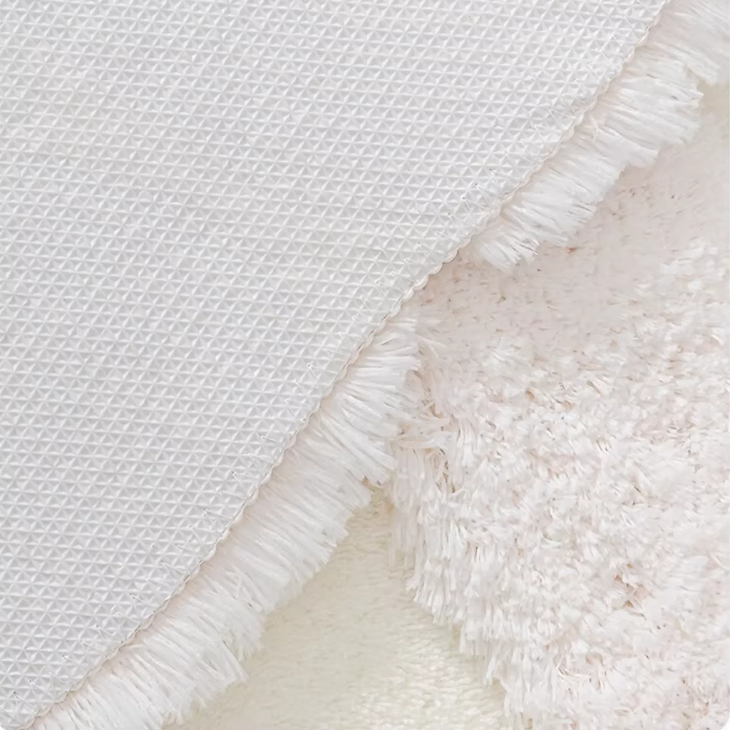 Eira Off White Irregular Cloud Patch High Low Tufted Rug by Housenfriends, detailed view of the grippy non-slip backing with the rug edge and fibres visible.