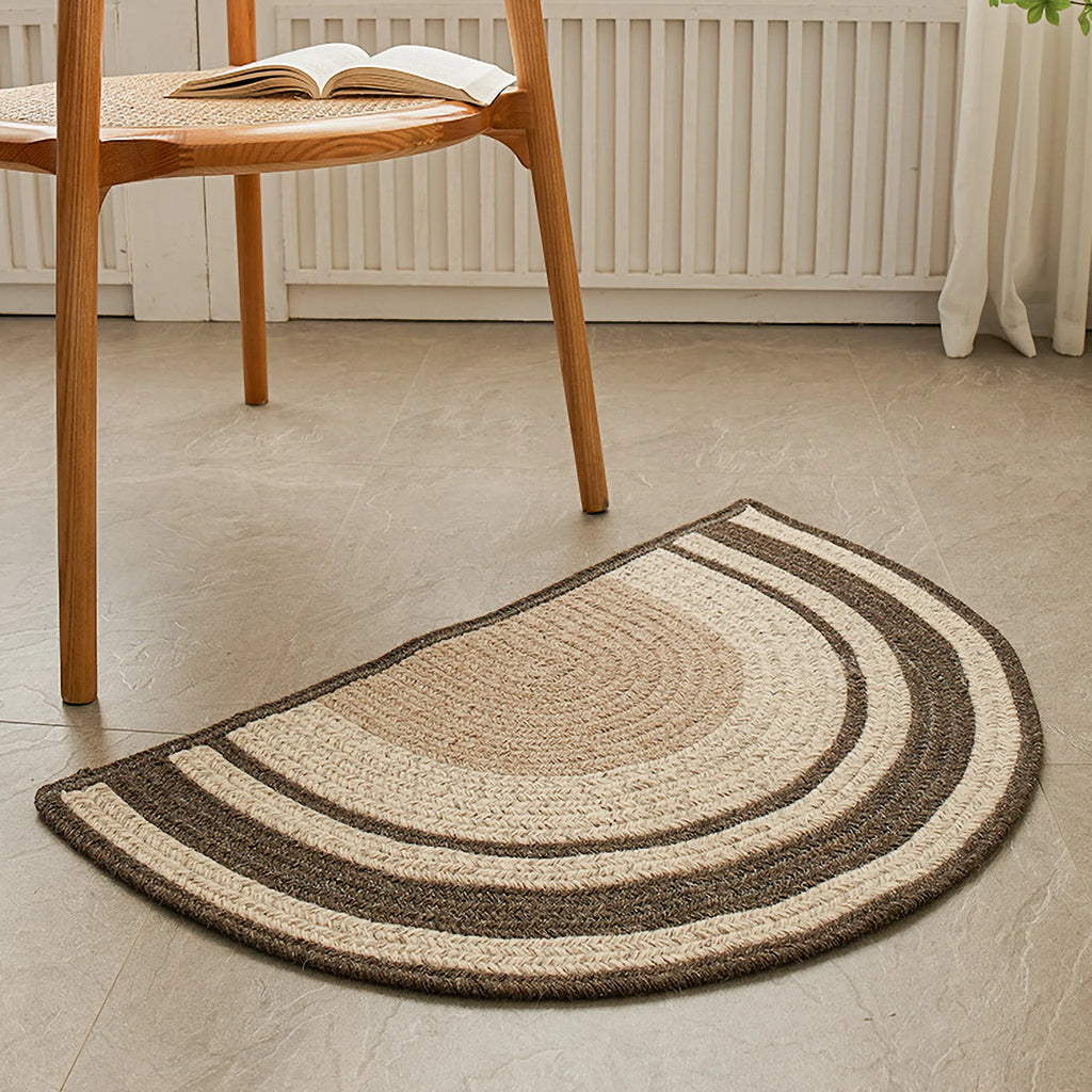 Elina Brown & Beige Wool-Blend Braided Half Moon Rug on a light wooden floor with a wooden chair in the background.
