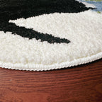 Close-up of a white and black textured rug on a wooden floor.