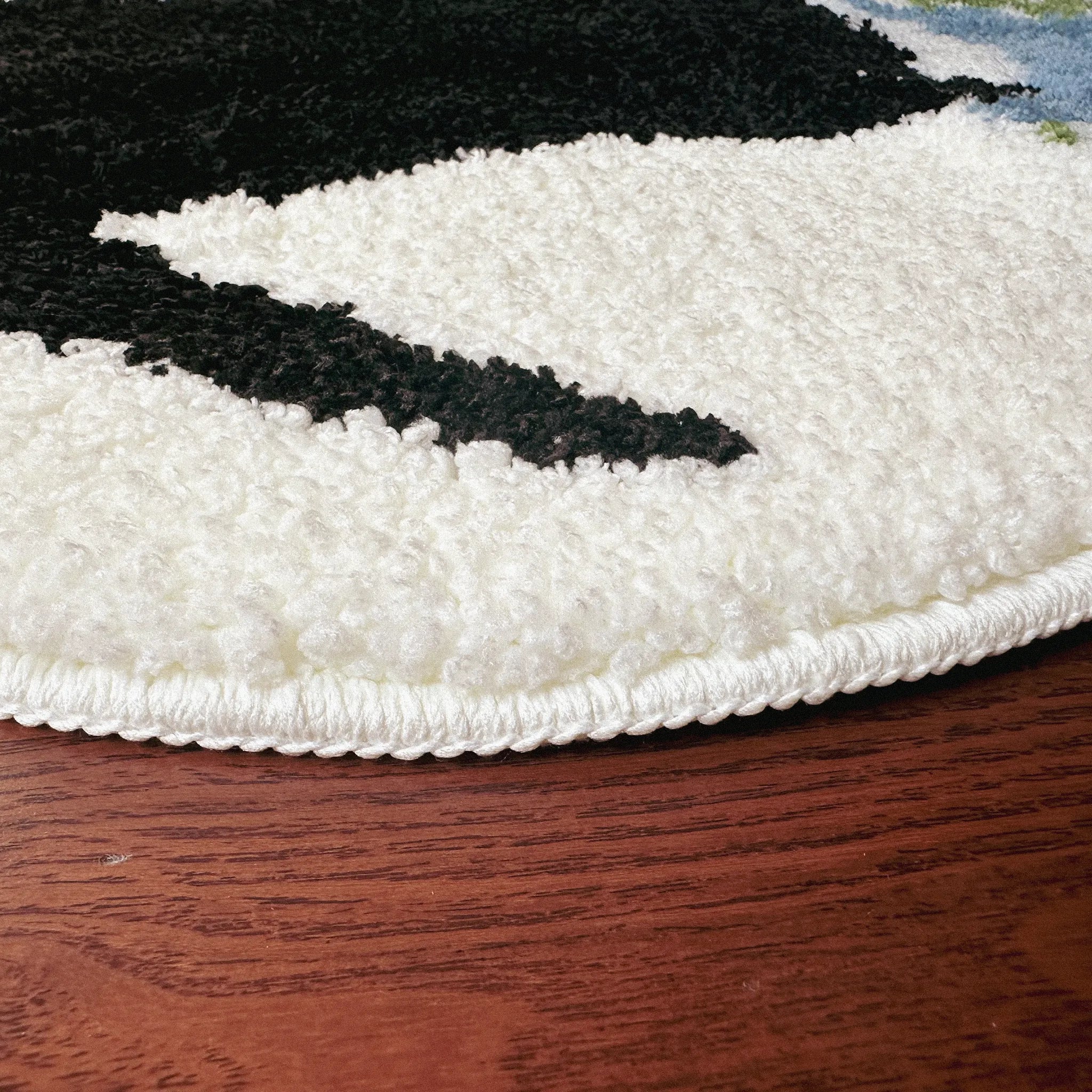 Close-up of a white and black textured rug on a wooden floor.
