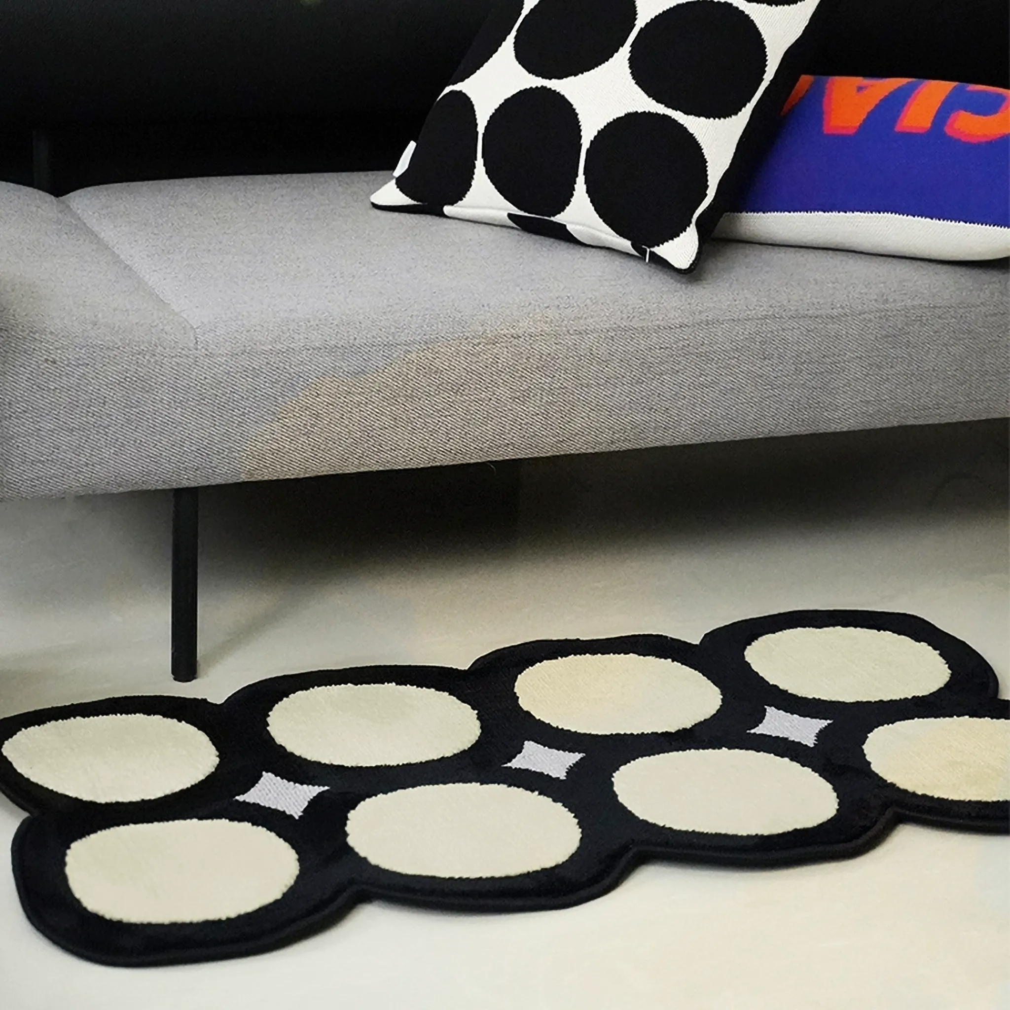 Harper Black and White Irregular Polka Dots Tufted Rug by Housenfriends on floor with a sofa and pillows.