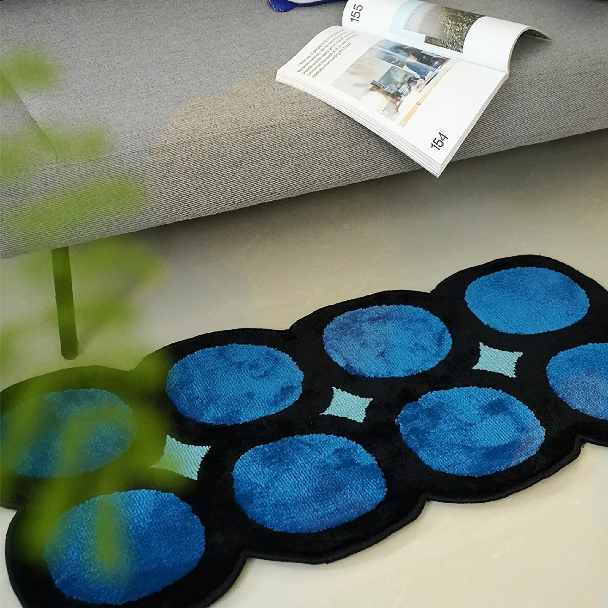Harper Blue and Black Irregular Polka Dots Tufted Rug by Housenfriends on floor with a magazine on sofa.