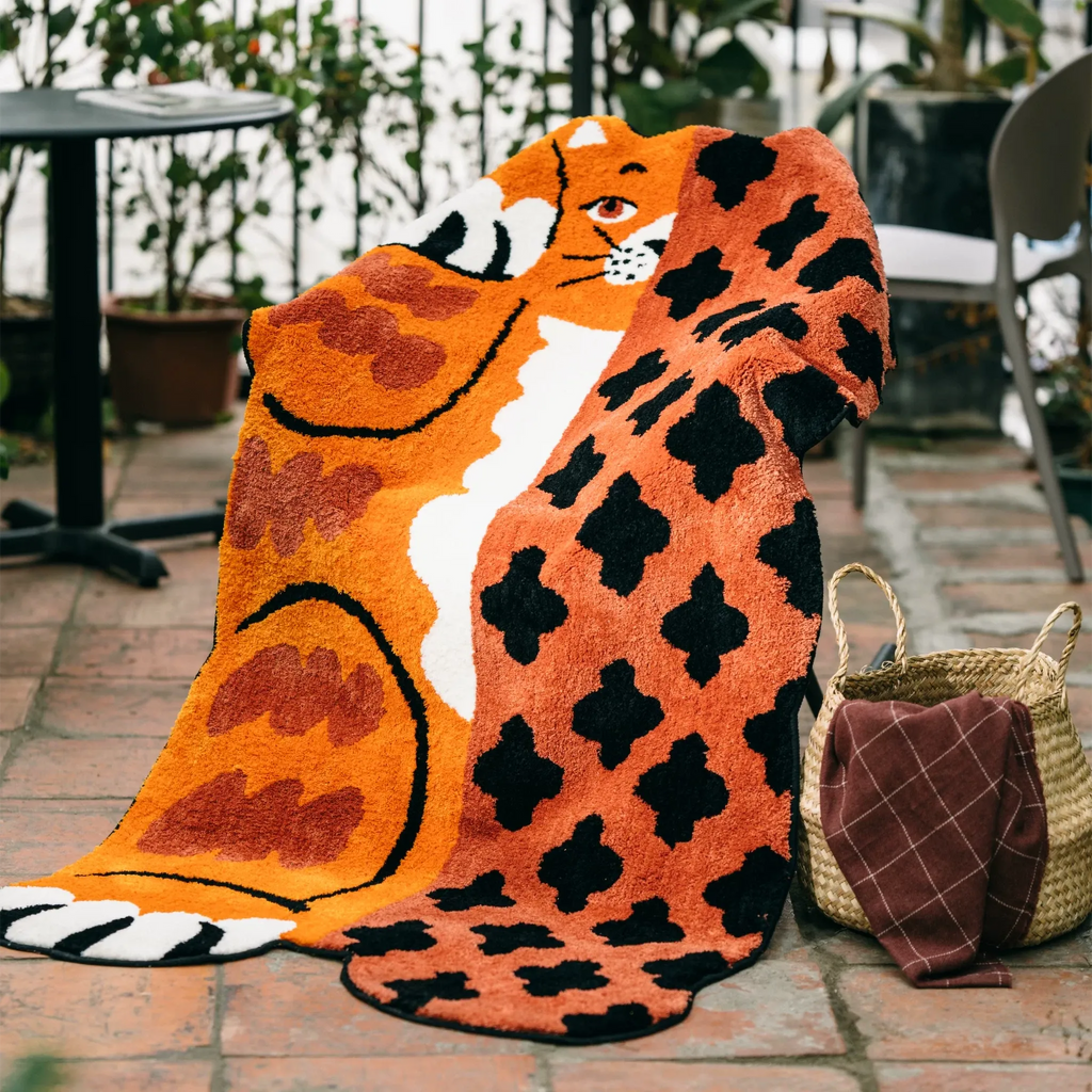 Hide and Seek orange cat shaped rug styled on a chair with bold patchwork markings and soft tufted texture by Housenfriends