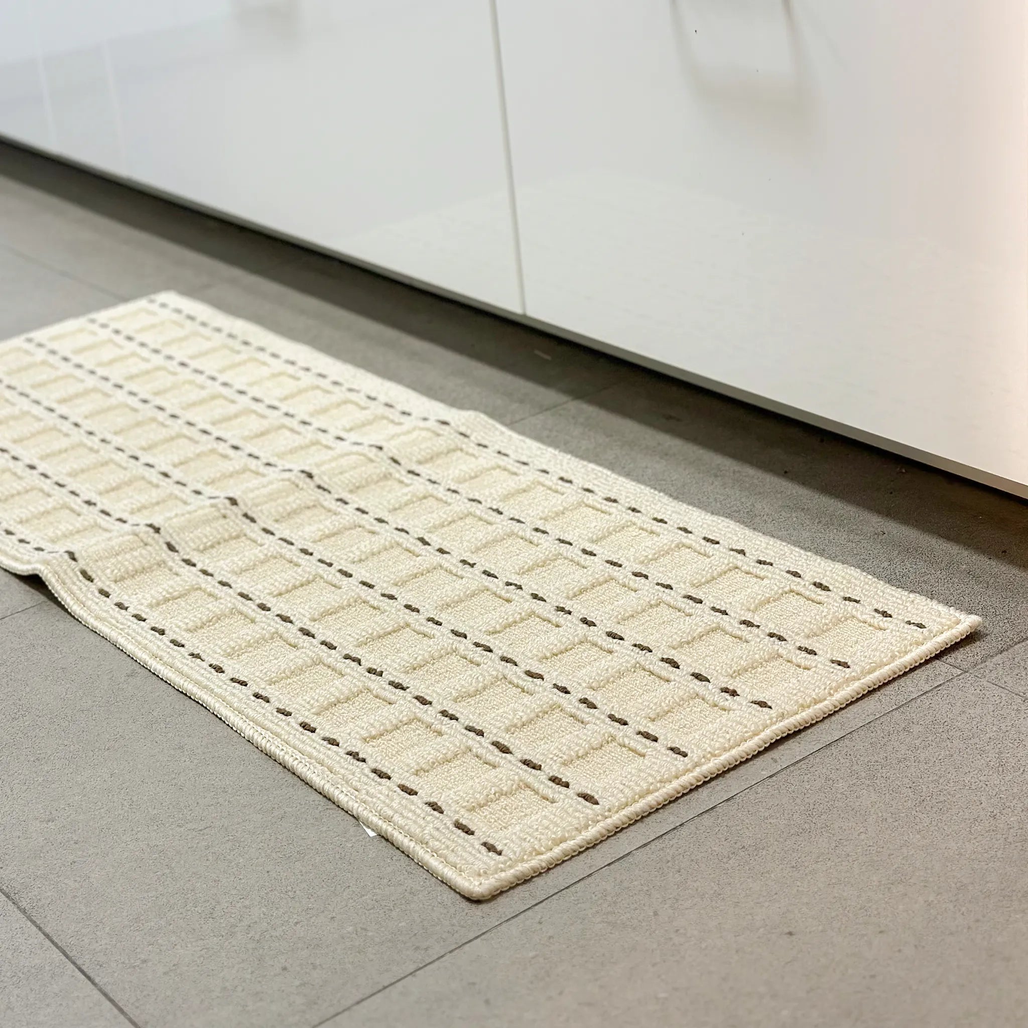 Housenfriends Ivo cream and mocha grid textured rug placed by sink area on tiled kitchen floor
