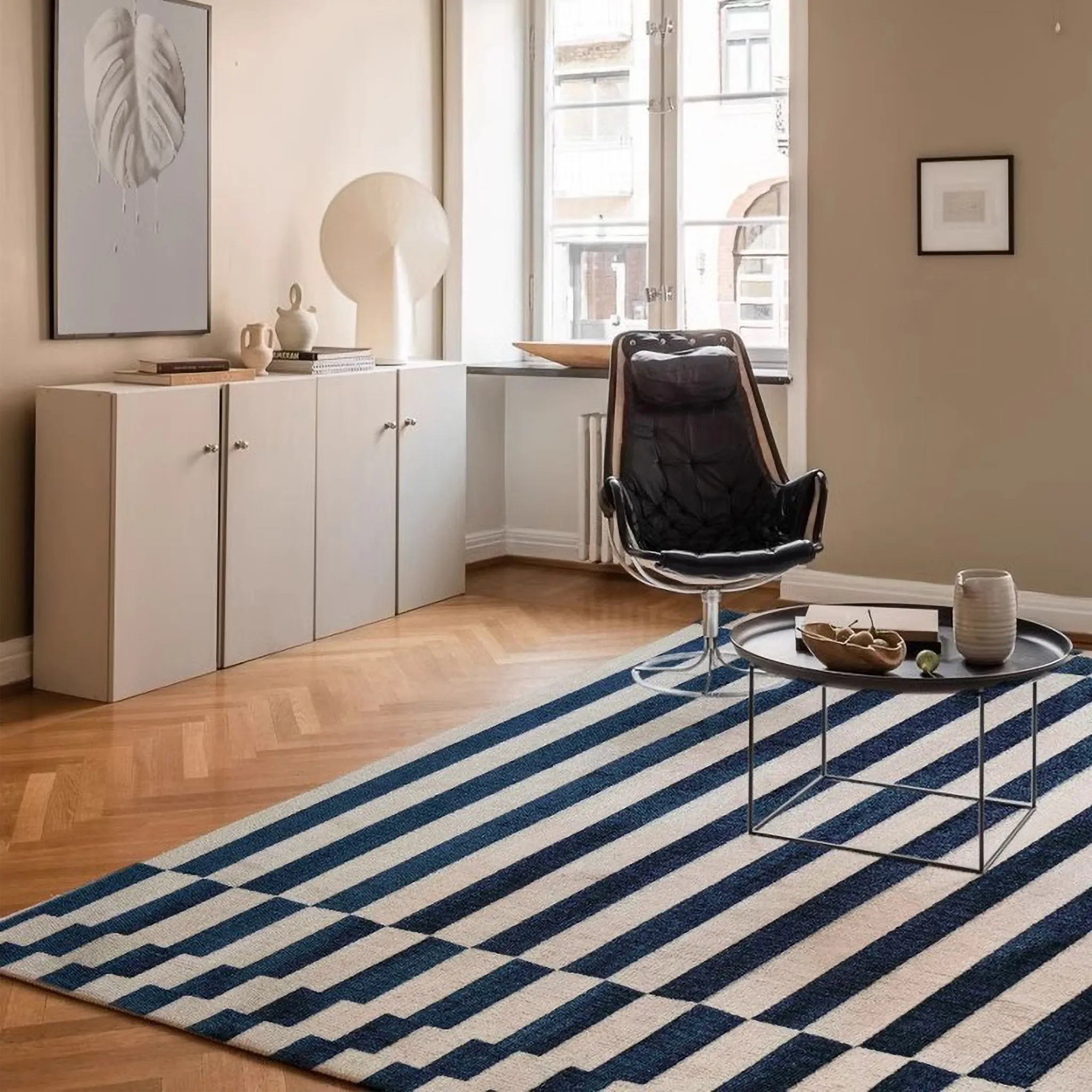 Living room with Julian Blue & White Offset Striped Modern Rug, black chair, and white cabinets.