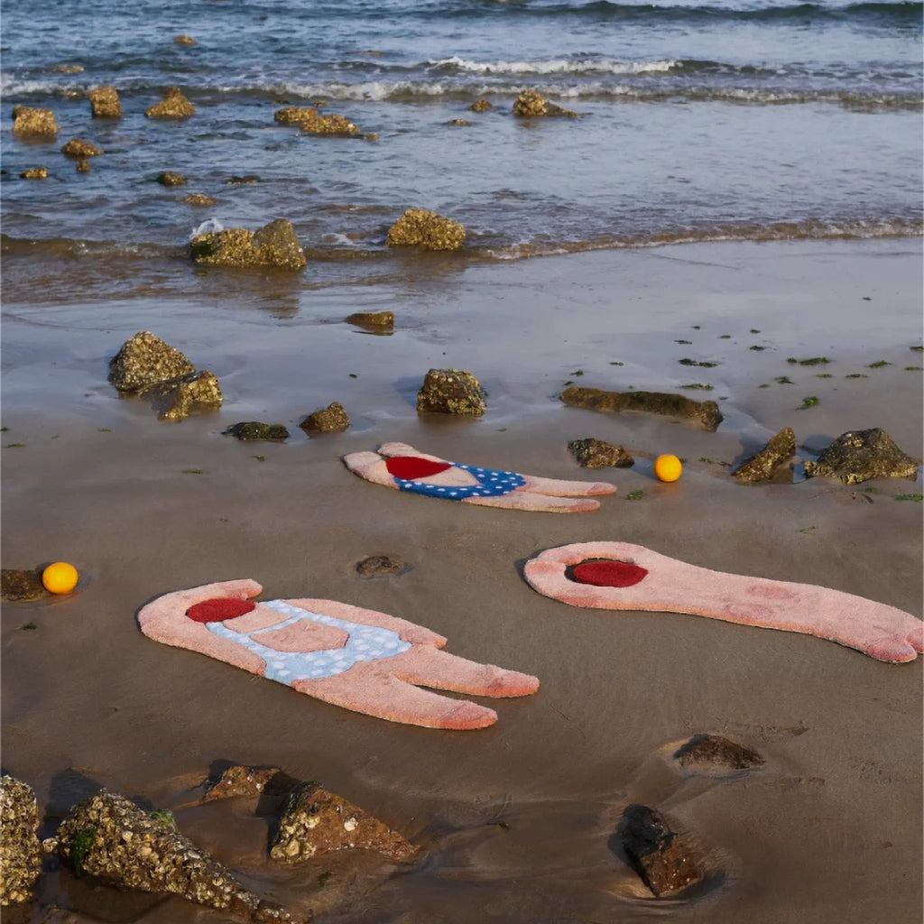 June seaside swimming girl rugs by Housenfriends on wet sand, featuring pale blue polka dot, navy swimsuit and nude curved back graphic body art tufted rugs
