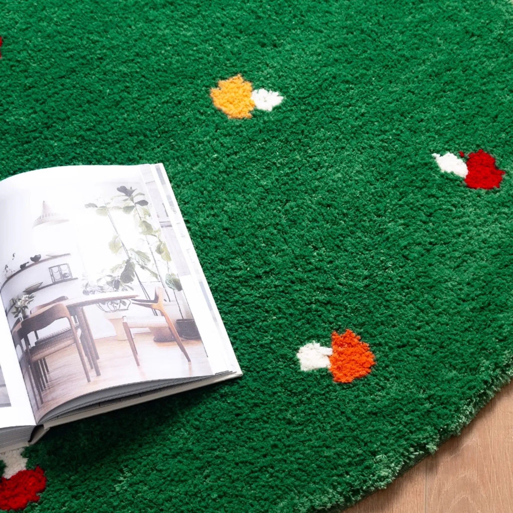 An open book on the Elora Moss Green Round Mushroom Tufted Rug by Housenfriends