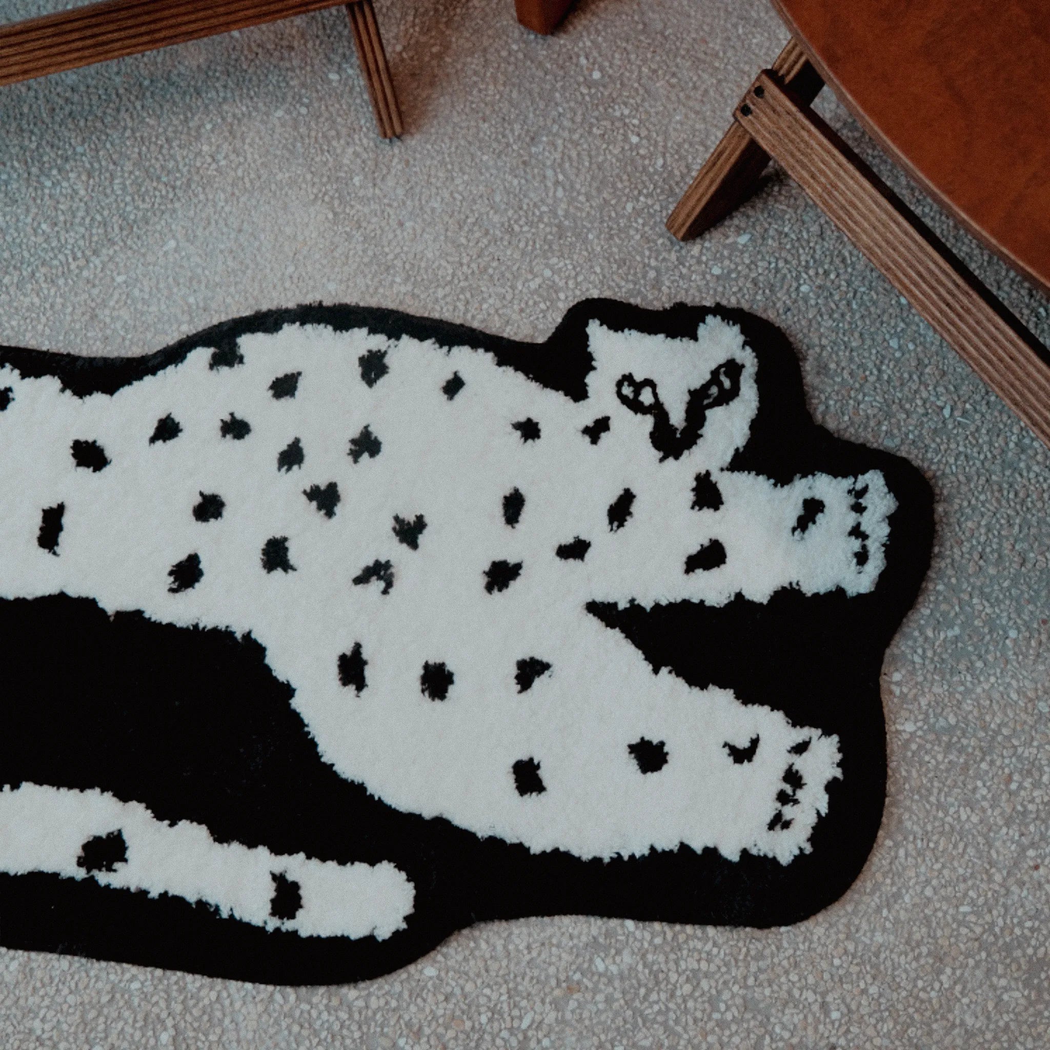Close-up of the Black Base White Leopard Shaped Tufted Rug on a carpeted floor