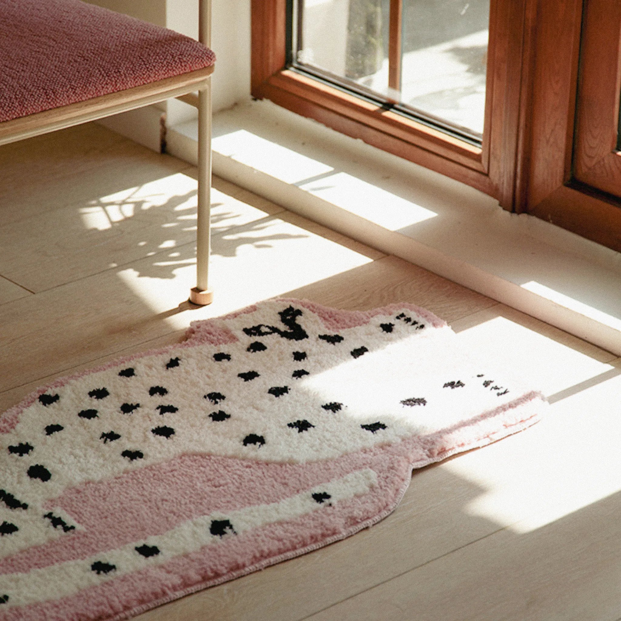 Blossom Pink Base White Leopard Shaped Tufted Rug on a wooden floor with a bench and window