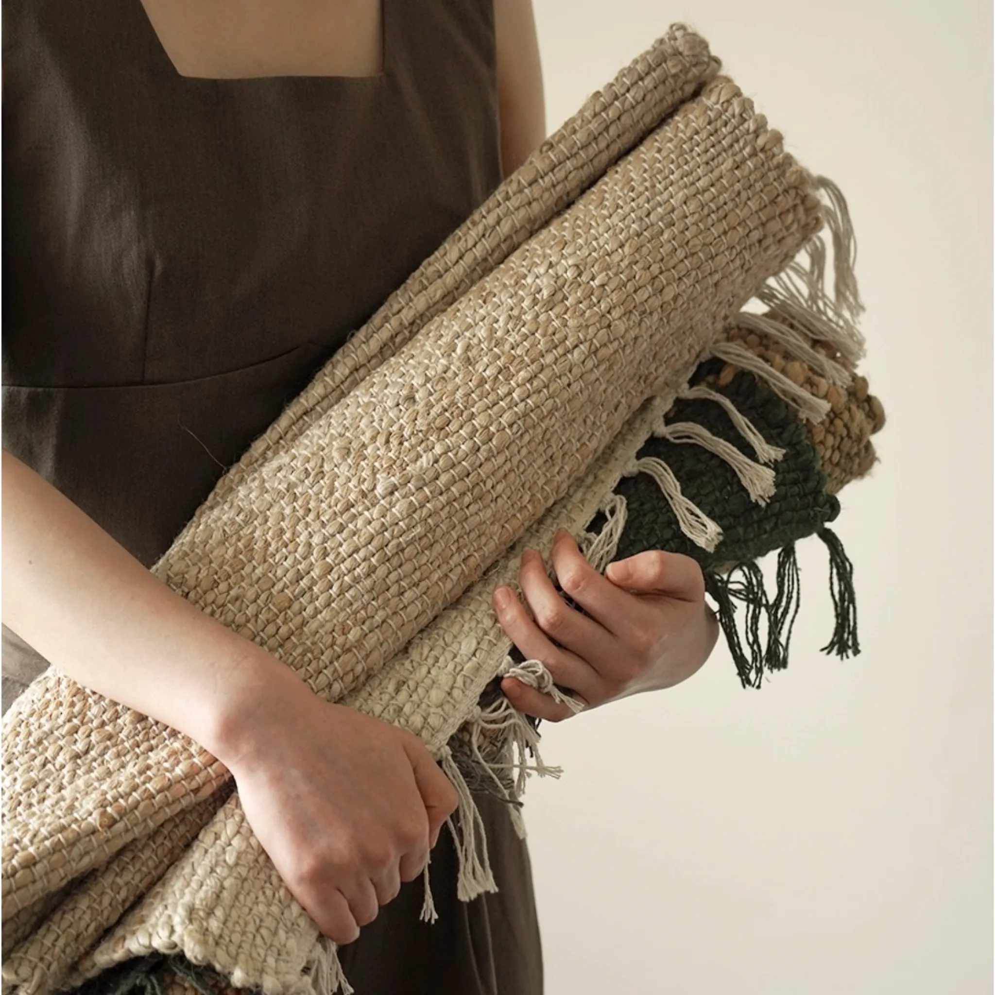 Maren handwoven jute rug in three colours held rolled up with fringed edge, Housenfriends