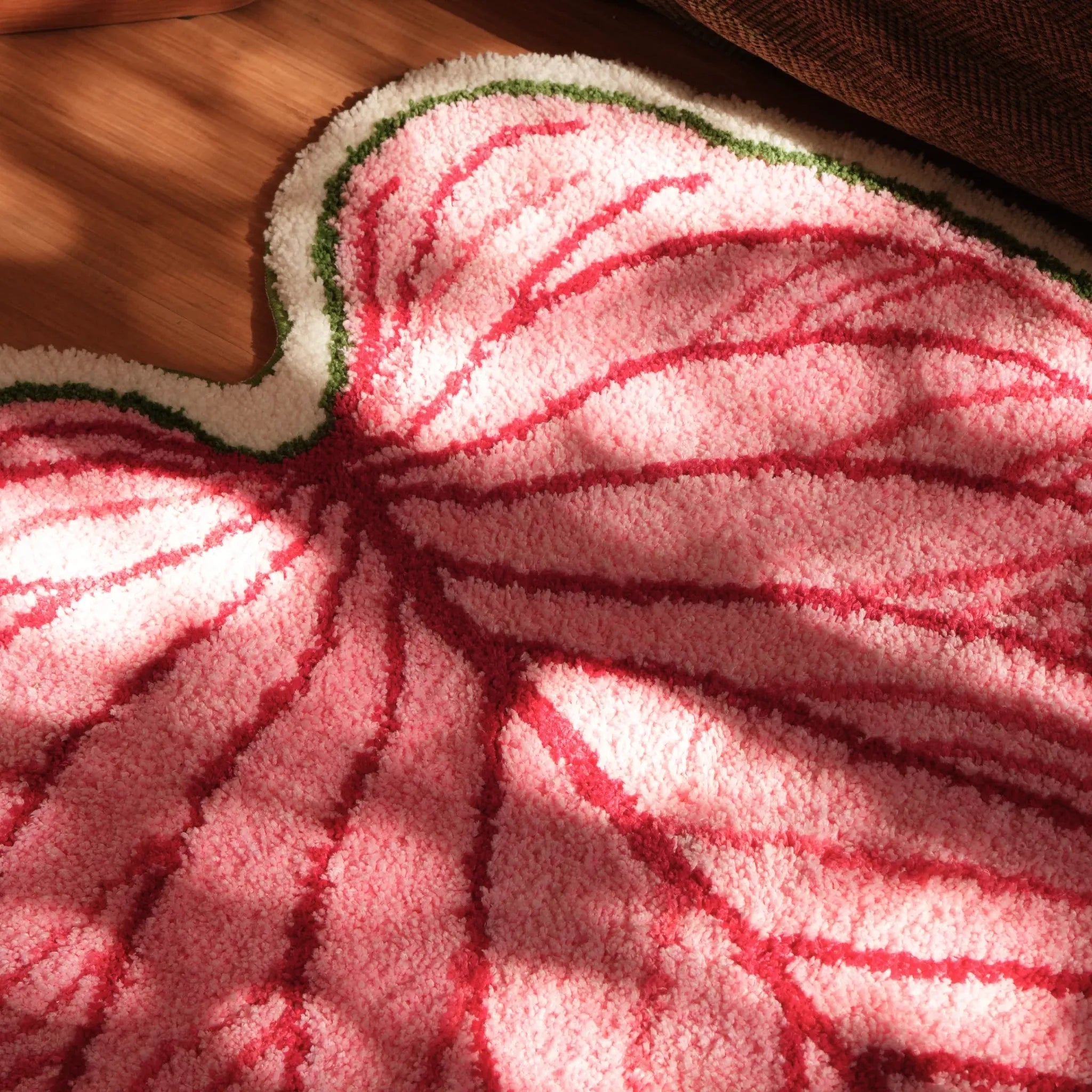 Close-up of Mina pink botanical heart leaf shaped tufted rug with raised red veins, green white border and textured pile by Housenfriends