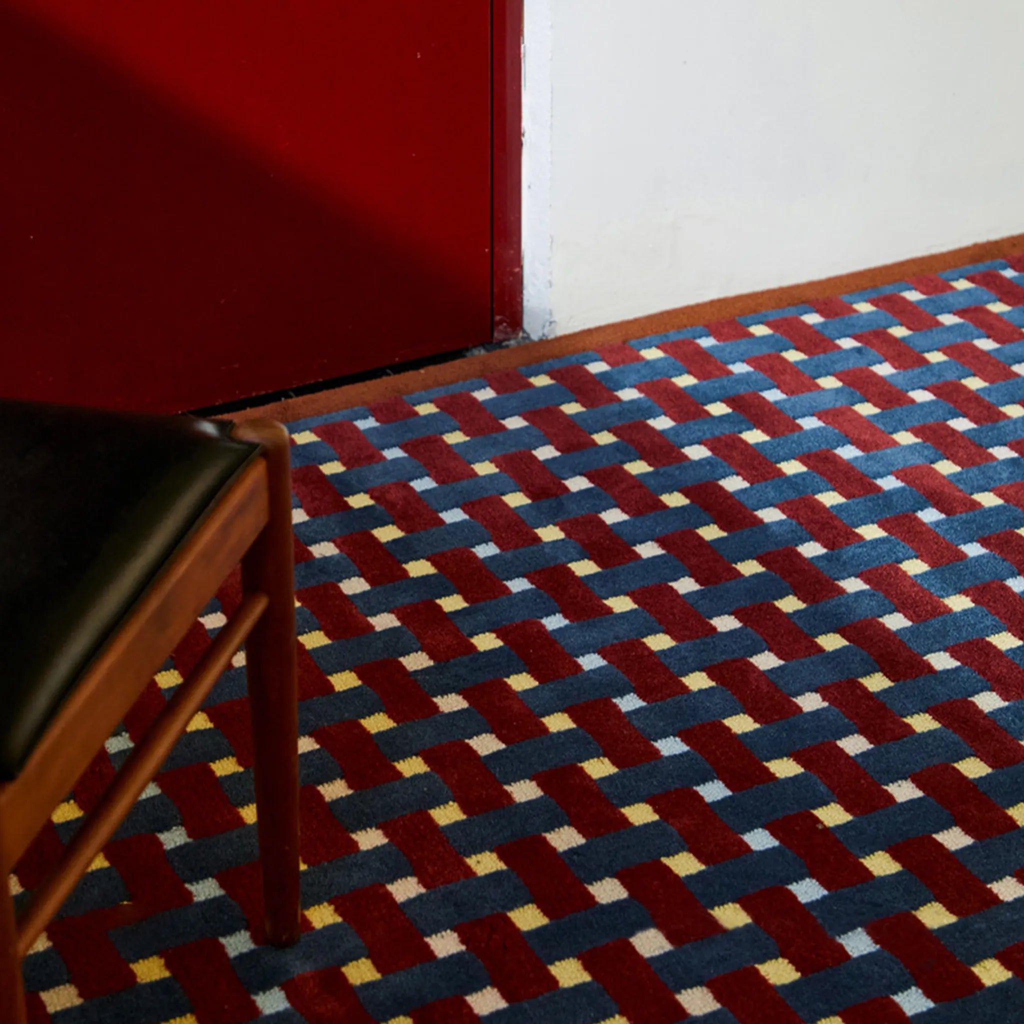 A chair on Mondrian Red Navy Beige Retro Checkered Wool Rug by Housenfriends