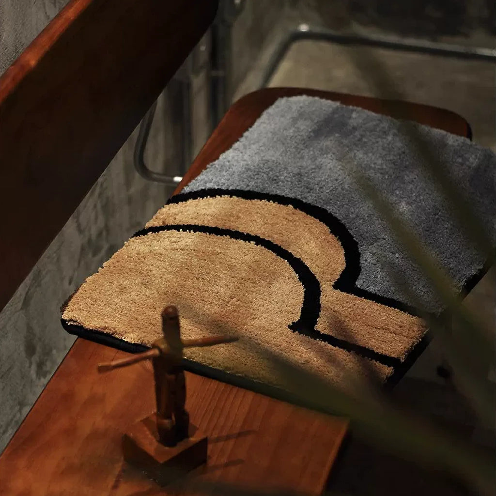 Nico Grey & Tan graphic abstract bum body art tufted rug on a wooden chair, showing soft pile texture, Housenfriends