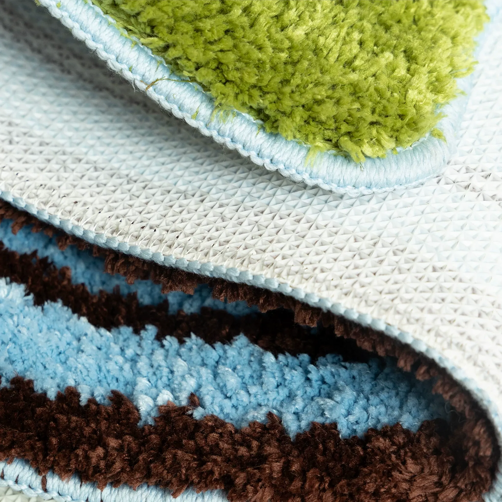 Detail of pastel blue and green sock shaped tufted rug with soft pile texture, stitched edge and non-slip backing by Housenfriends