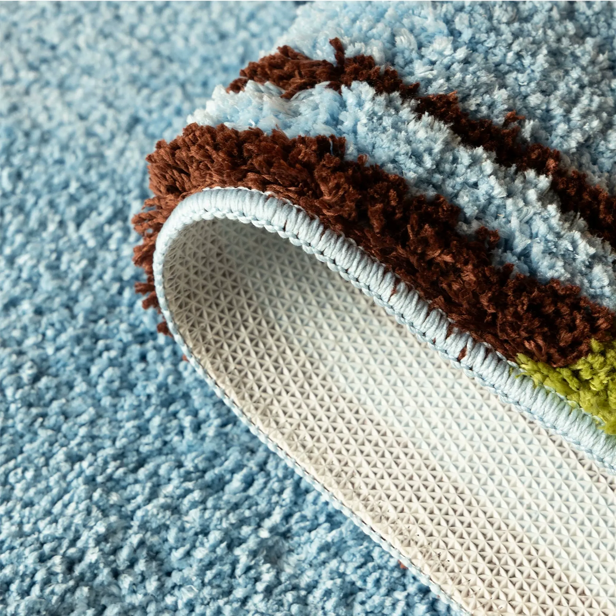Close up of blue and green colourblock sock shaped tufted rug showing soft blue pile and non-slip backing by Housenfriends