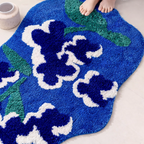 Top view of Orla blue floral shaped high-low tufted rug (80×120cm), navy blooms with white outlines and moss green leaves