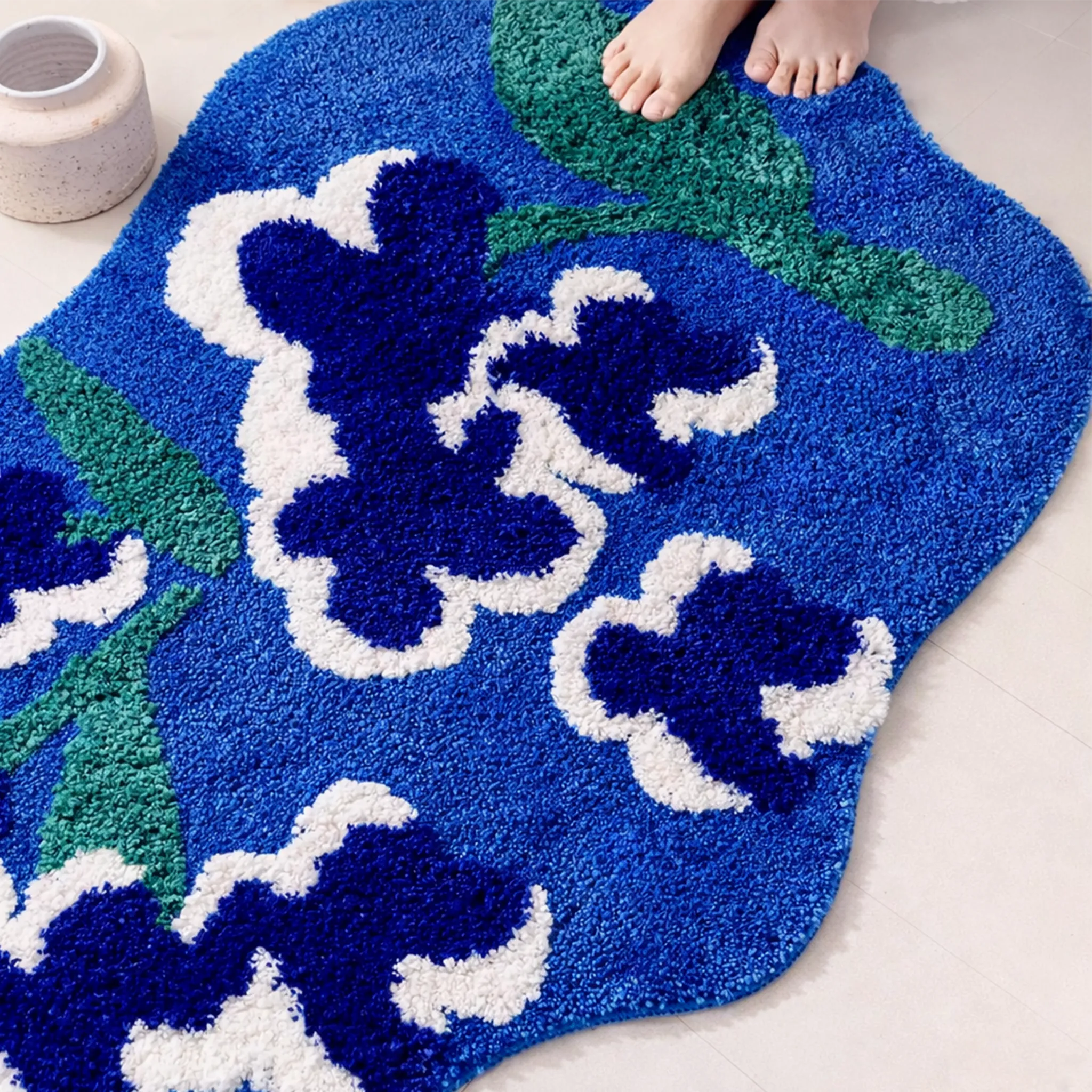 Top view of Orla blue floral shaped high-low tufted rug (80×120cm), navy blooms with white outlines and moss green leaves