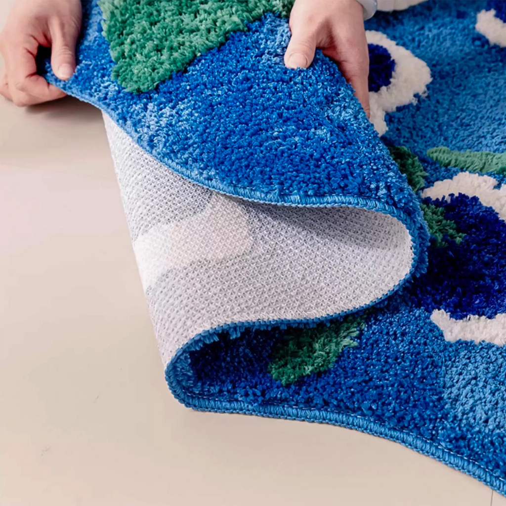 Orla shaped tufted small rug folded to show the non-slip backing, high-low pile and thick tufted edge