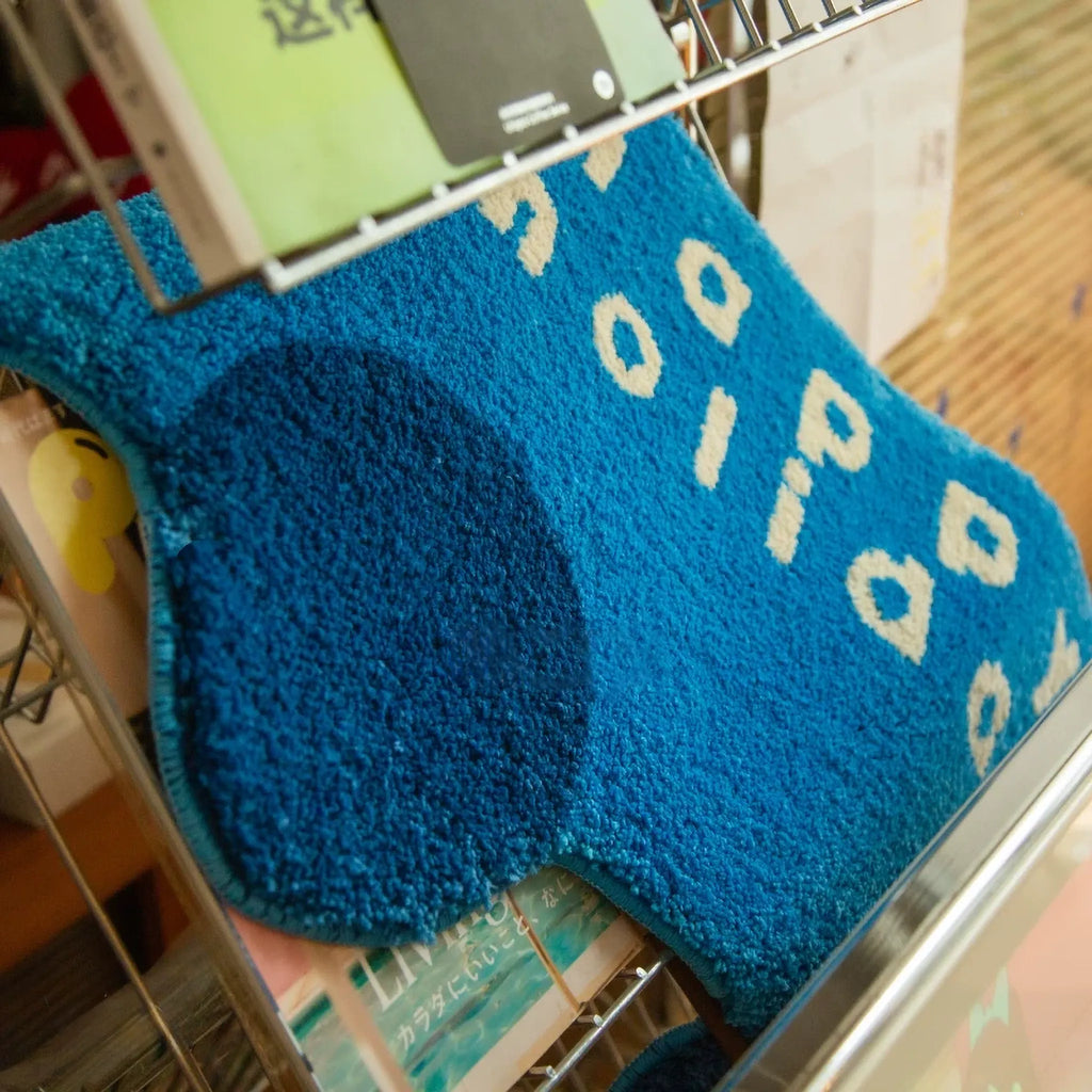 Pip Blue & Navy Happy Holiday Graphic Car Shaped Tufted Rug by Housenfriends on shelf, blue shaggy graphic car rug with cream word art and navy wheels