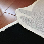 Close-up of texture fabric and a white non-slip backing of Playful Black Jumping Cat Shaped Designer Tufted Rug