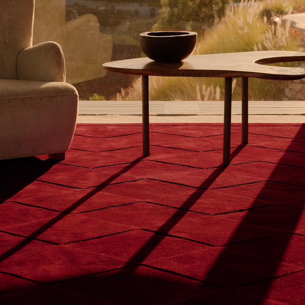 Burgundy Diamond Modern High Low Hand Tufted Rug in a room with a table and chair, illuminated by the soft light of the setting sun.