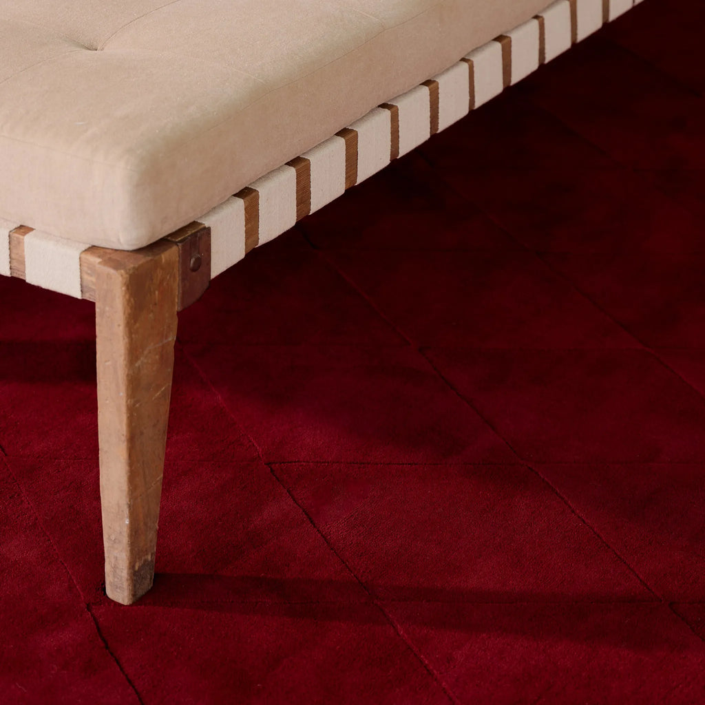 Beige cushioned bench with wooden legs on the Burgundy Diamond Modern High Low Hand Tufted Rug