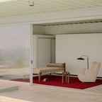 Modern living room with a Burgundy Diamond Modern High Low Hand Tufted Rug, beige armchair, and wooden bench.