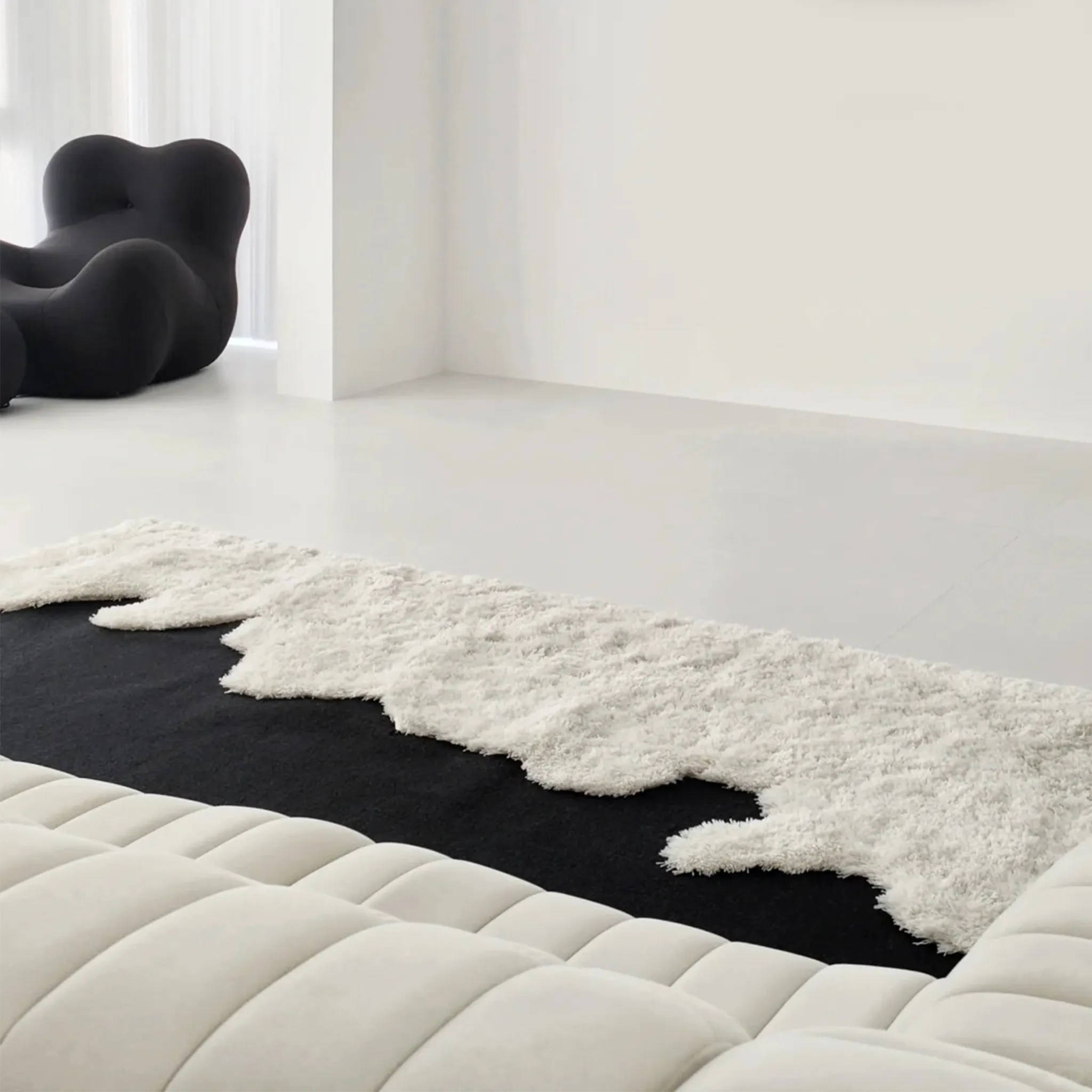 Reynisfjara Black Shore White Waves Abstract High Low Rug by Housenfriends on a white floor with a modern chair and sofa.
