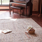 Wooden piano in a room with an open book and a basket on Rowan Neutral Multi-Tone Wool & Jute Handwoven Rug.