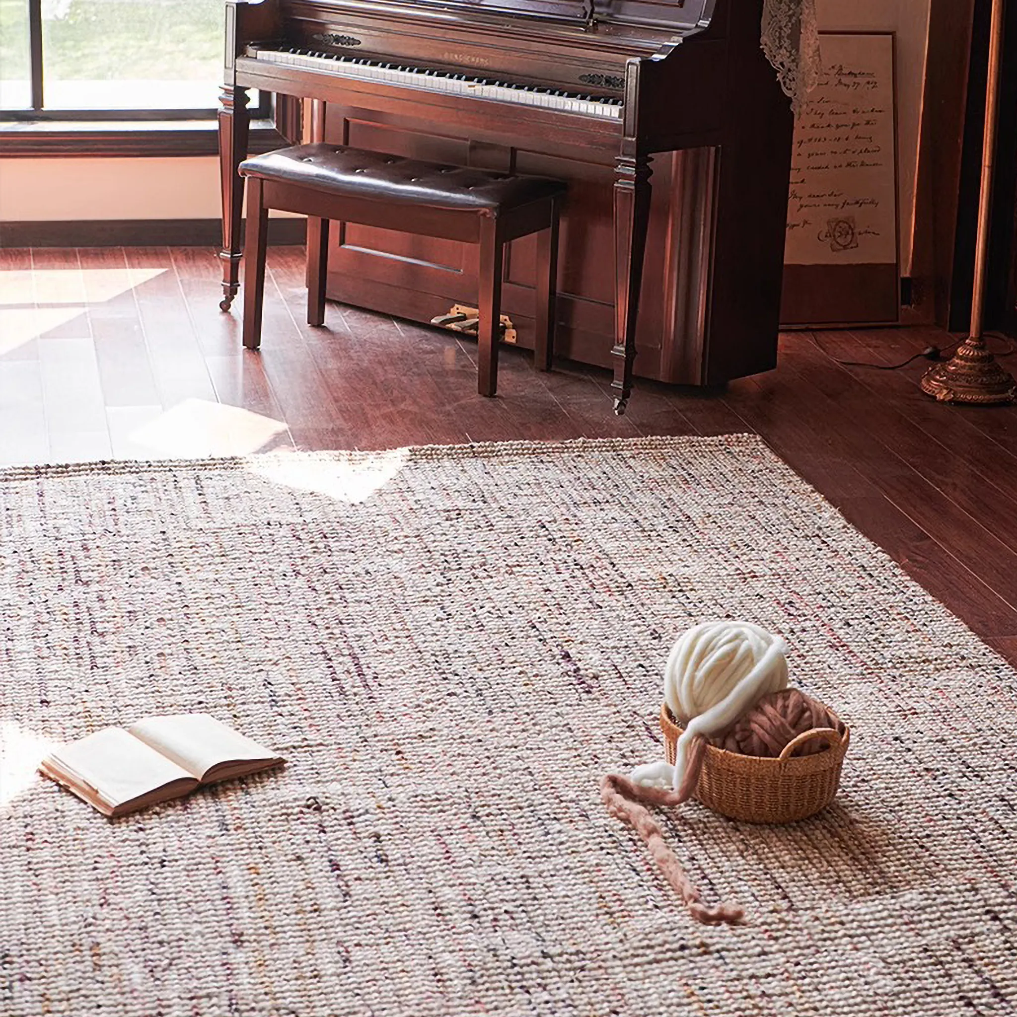 Wooden piano in a room with an open book and a basket on Rowan Neutral Multi-Tone Wool & Jute Handwoven Rug.