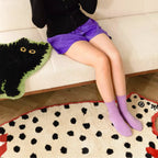 Person sitting on a couch with Cheeky Fart Puff Red White Leopard Shaped Tufted Rug