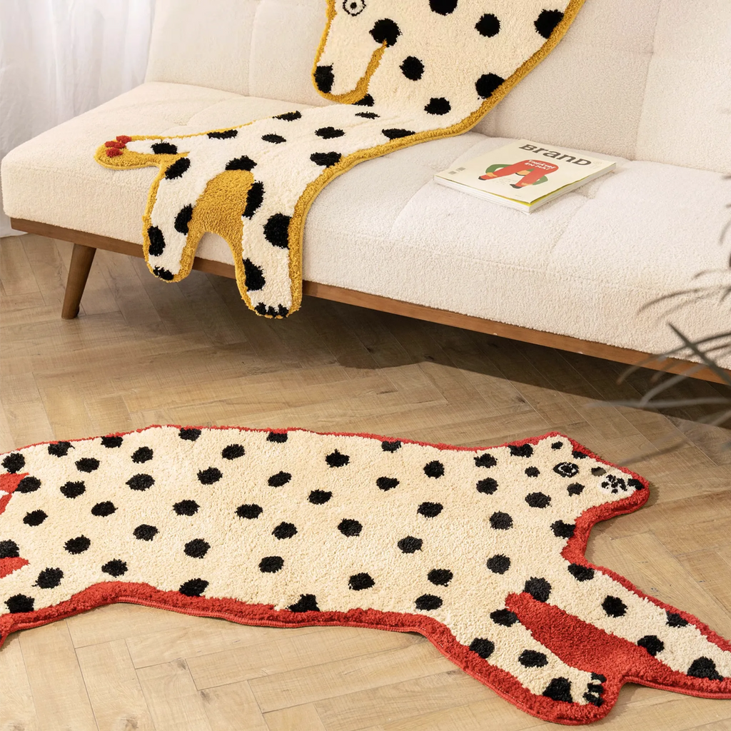 Red Outlined White Leopard Shaped Rug on a wooden floor, with a Dalmatian Yellow Outlined White Dog Rug displayed on the couch behind.