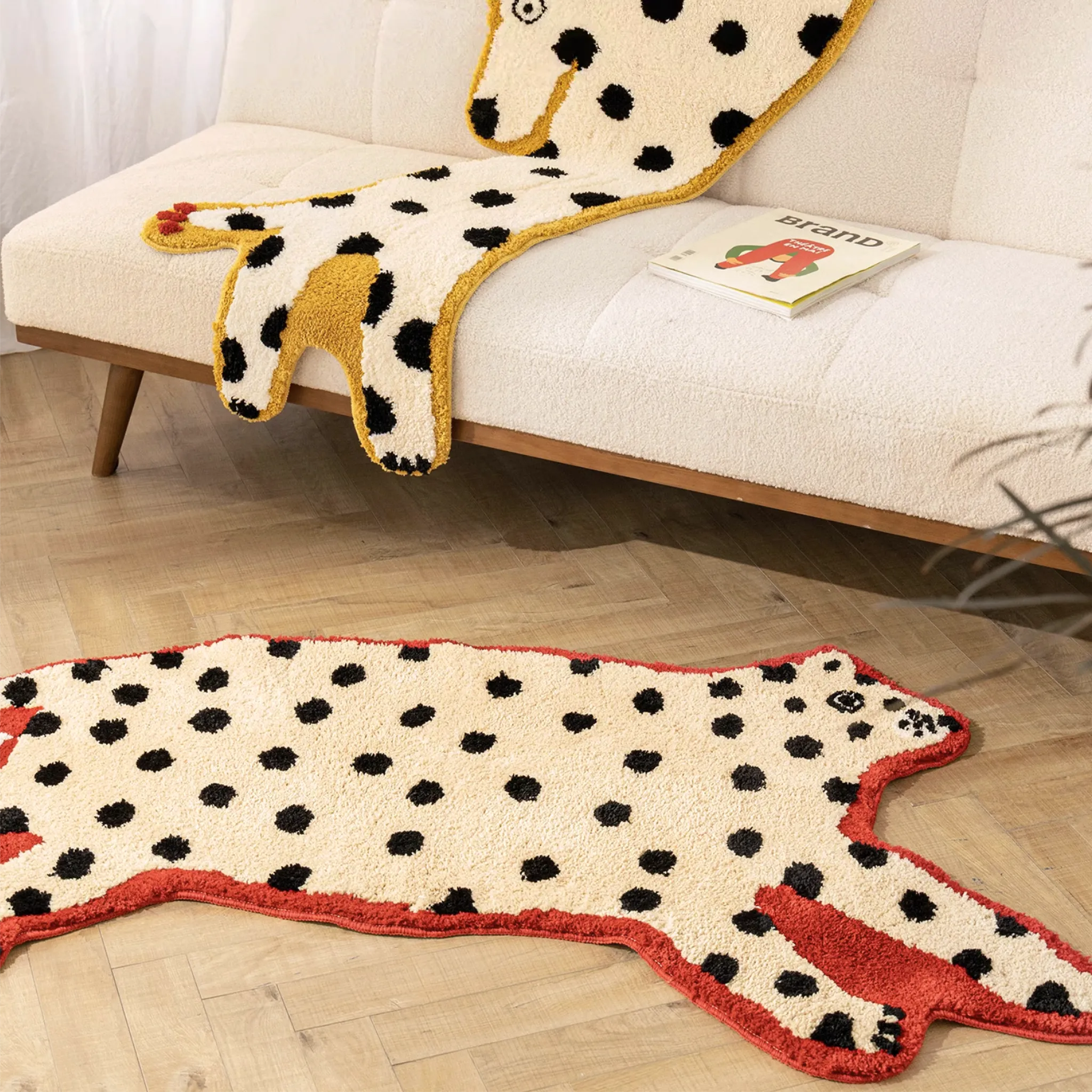 Red Outlined White Leopard Shaped Rug on a wooden floor, with a Dalmatian Yellow Outlined White Dog Rug displayed on the couch behind.