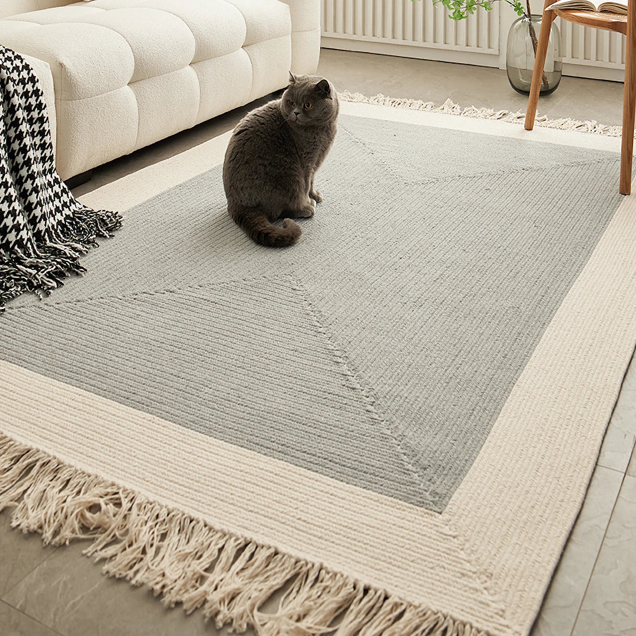 Housenfriends Signe rectangular braided cotton-blend rug in grey and natural, fringe detail at the edge in a modern living room