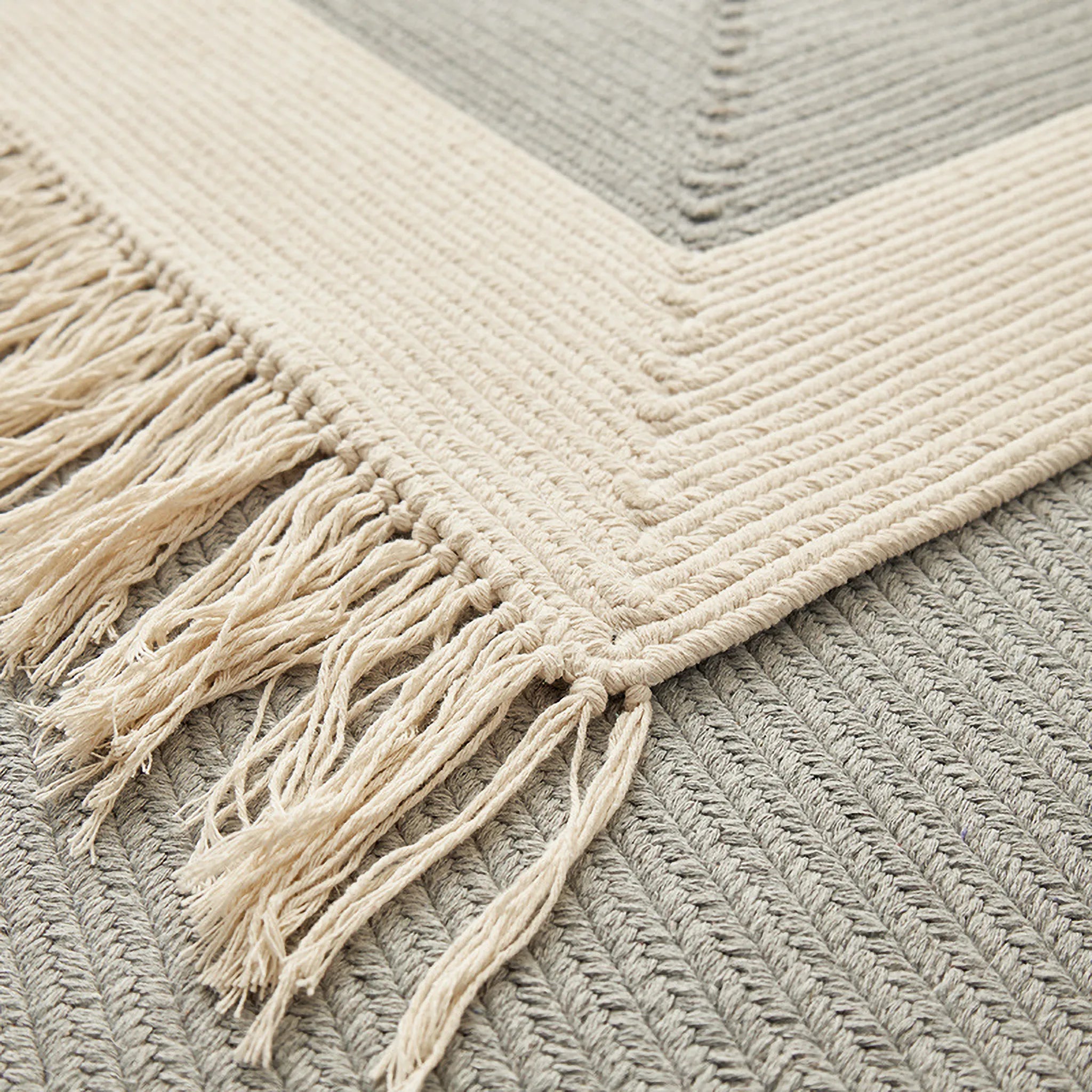 Close-up of the Signe rug corner, hand-braided texture in natural cotton tone with relaxed fringe by Housenfriends