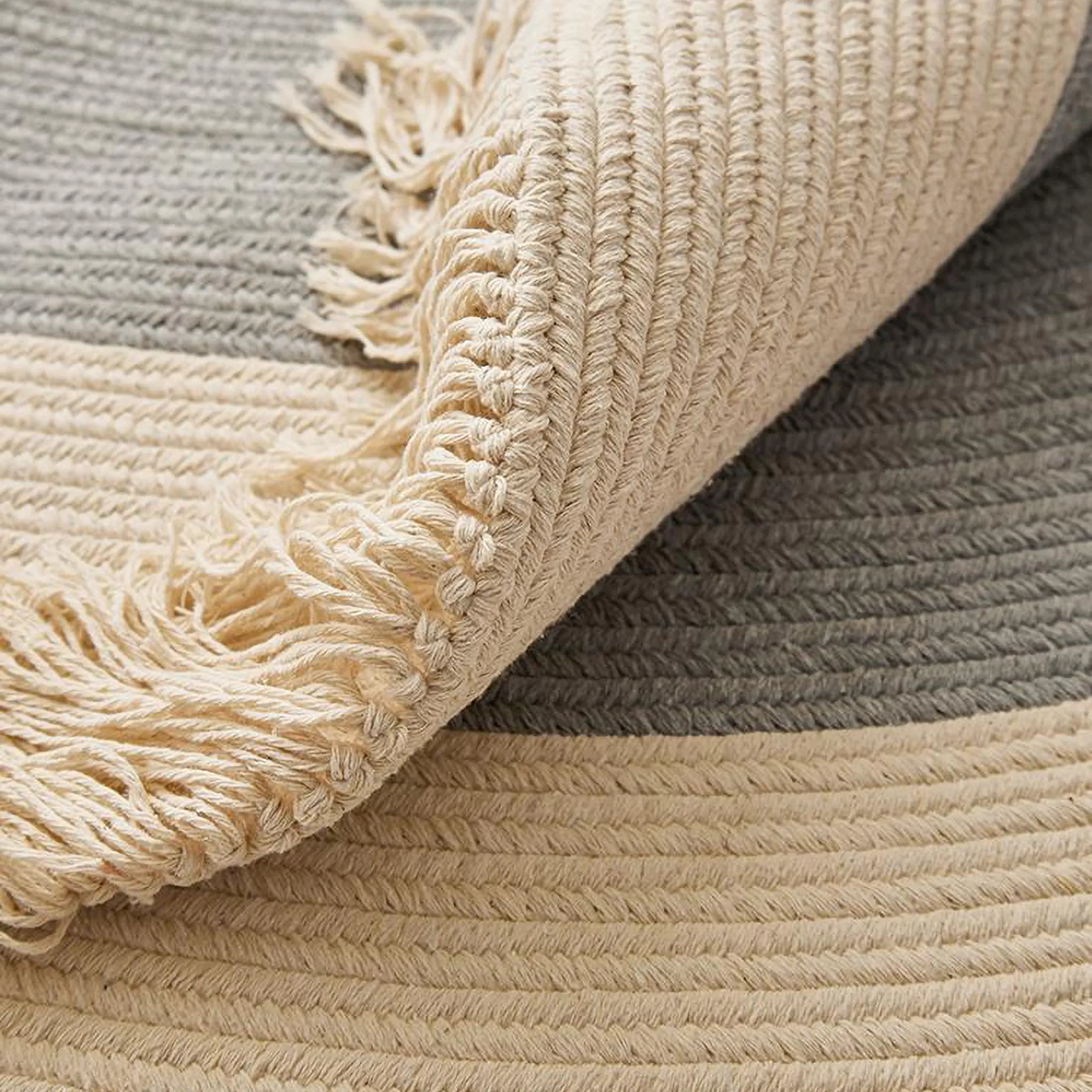 Signe grey and natural fringed round hand-braided cotton blend rug folded corner showing braid texture and fringe by Housenfriends