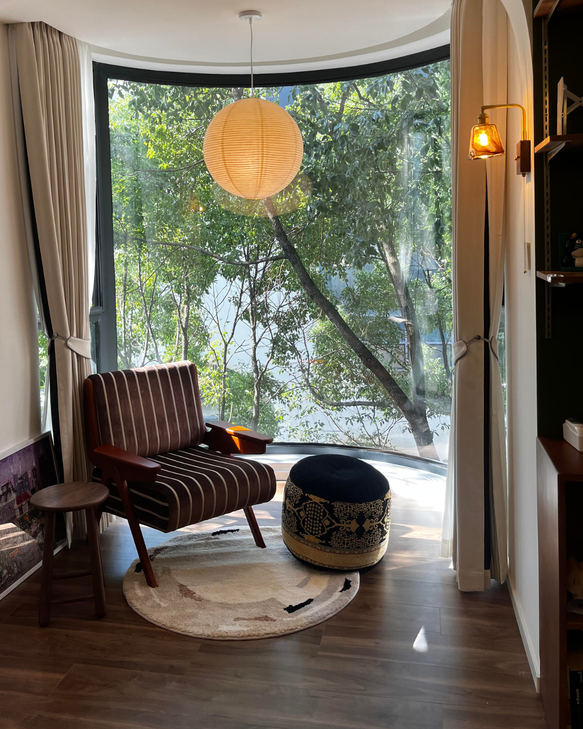 Housenfriends Elodie cream and beige abstract round rug in a reading nook with an armchair and footstool.