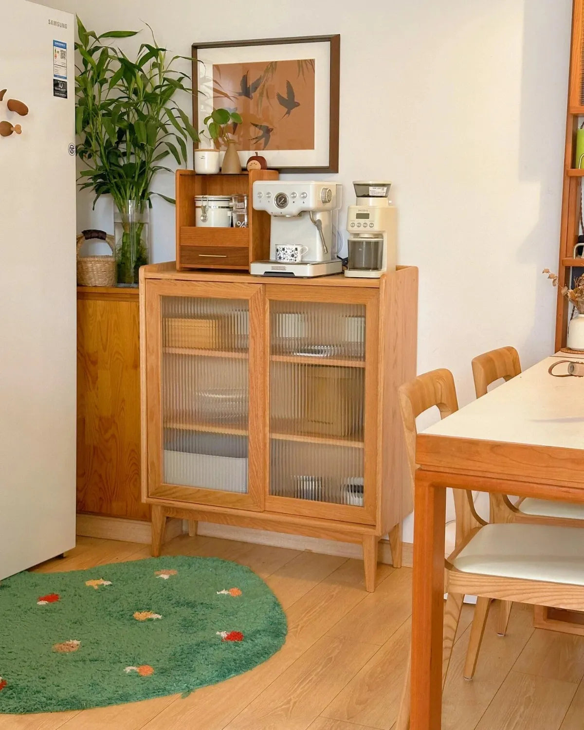 Housenfriends Elora moss green mushroom rug beside a coffee station and dining table, 100 × 100 cm.