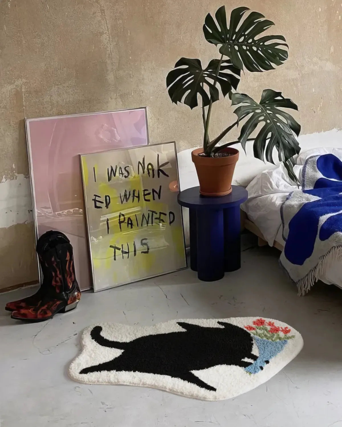 Housenfriends floral black cat tufted rug beside a bed in an eclectic bedroom with blue accents.