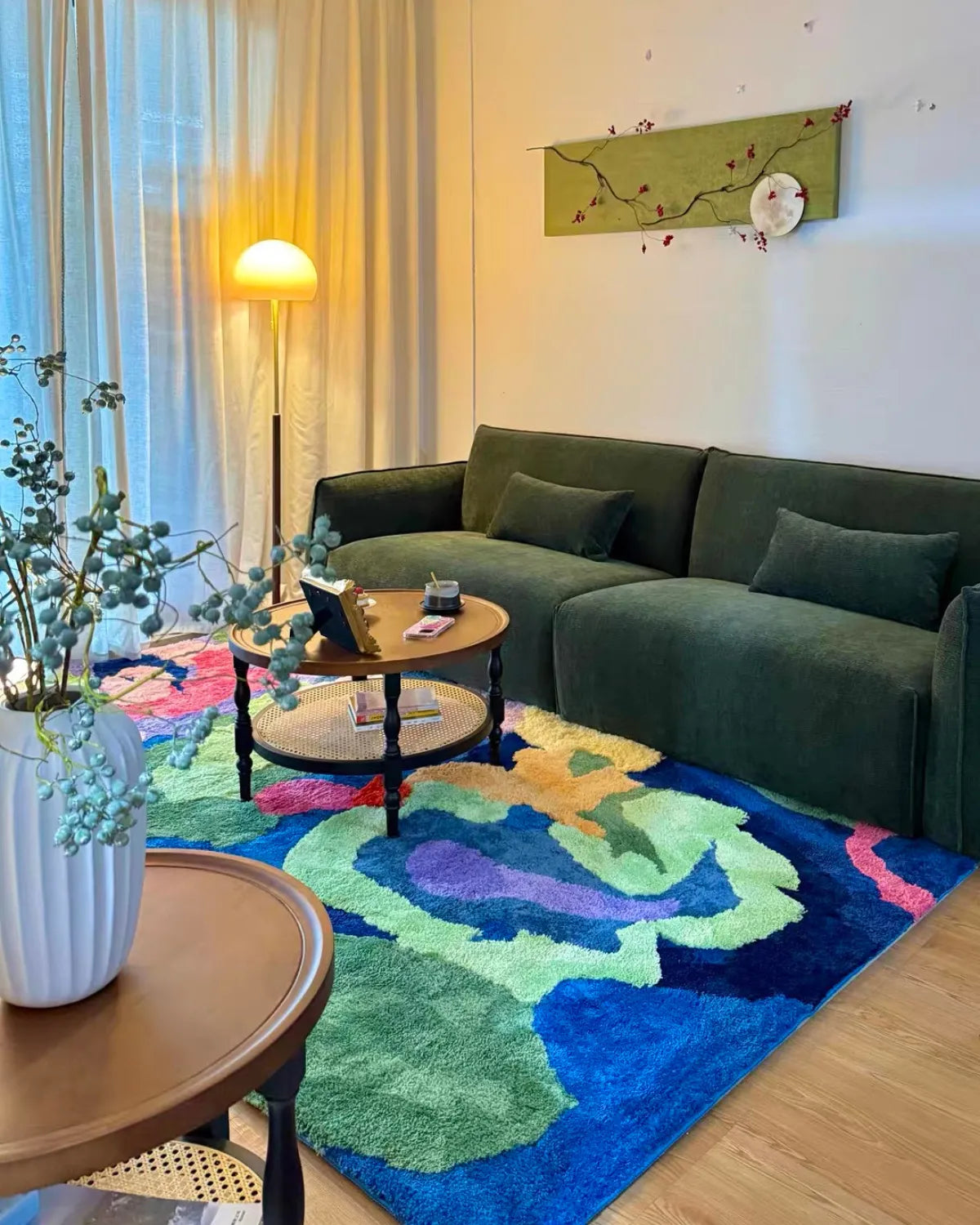 Housenfriends Freya multicoloured abstract floral high-low tufted rug beside a green sofa and round coffee table in a living room.
