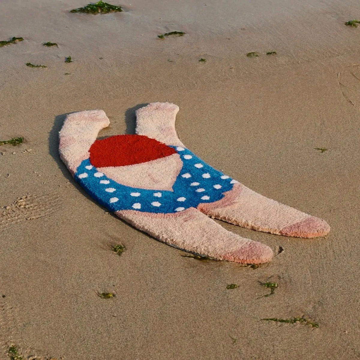 June Navy Polka Dot Swimsuit Swimming Girl Body Art Tufted Rug by Housenfriends, featuring red-brown hair, a blue swimsuit with white polka dots and raised arms, on a sandy beach.